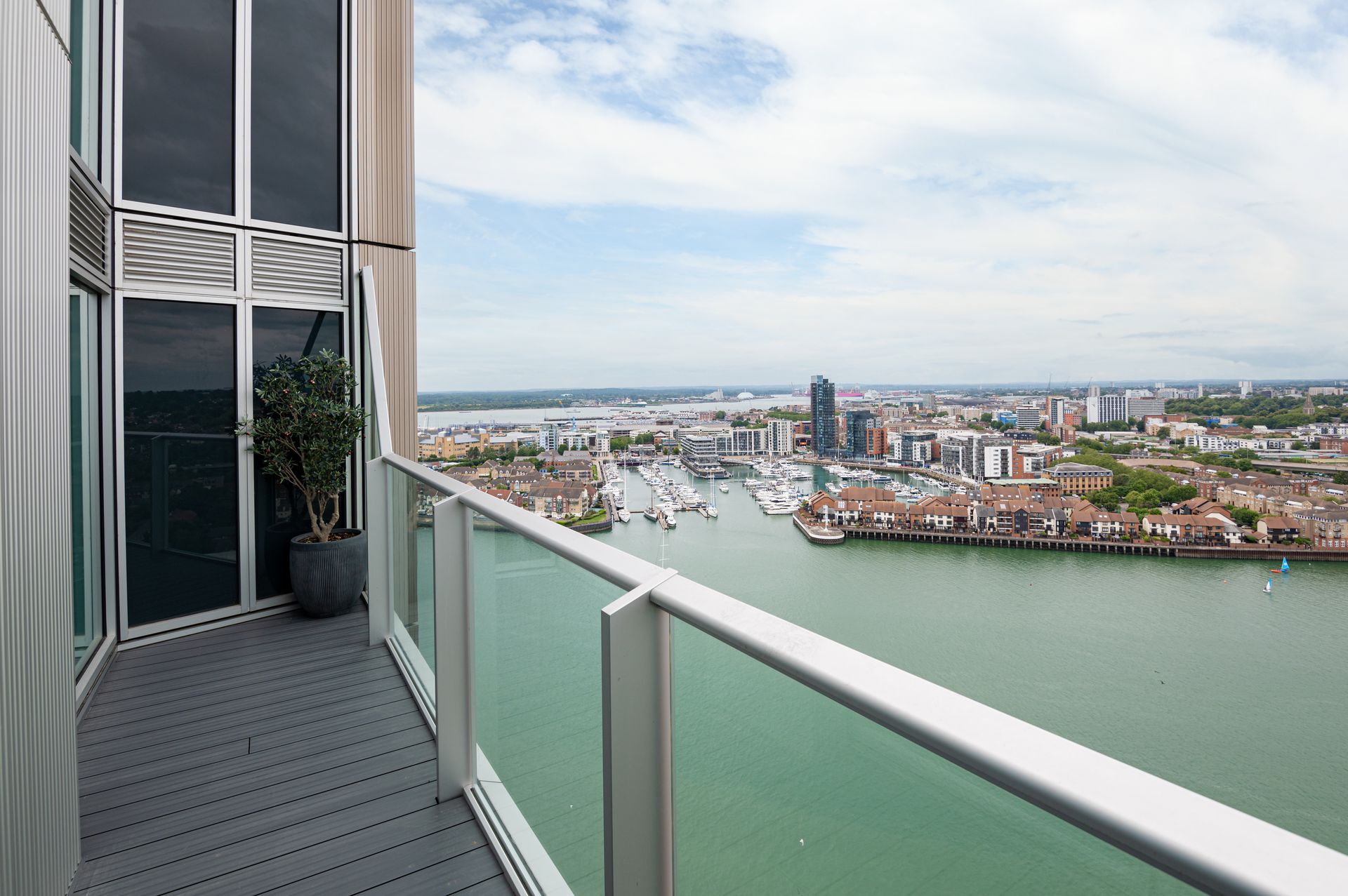 Balcony overlooking a marina and city skyline under a bright sky