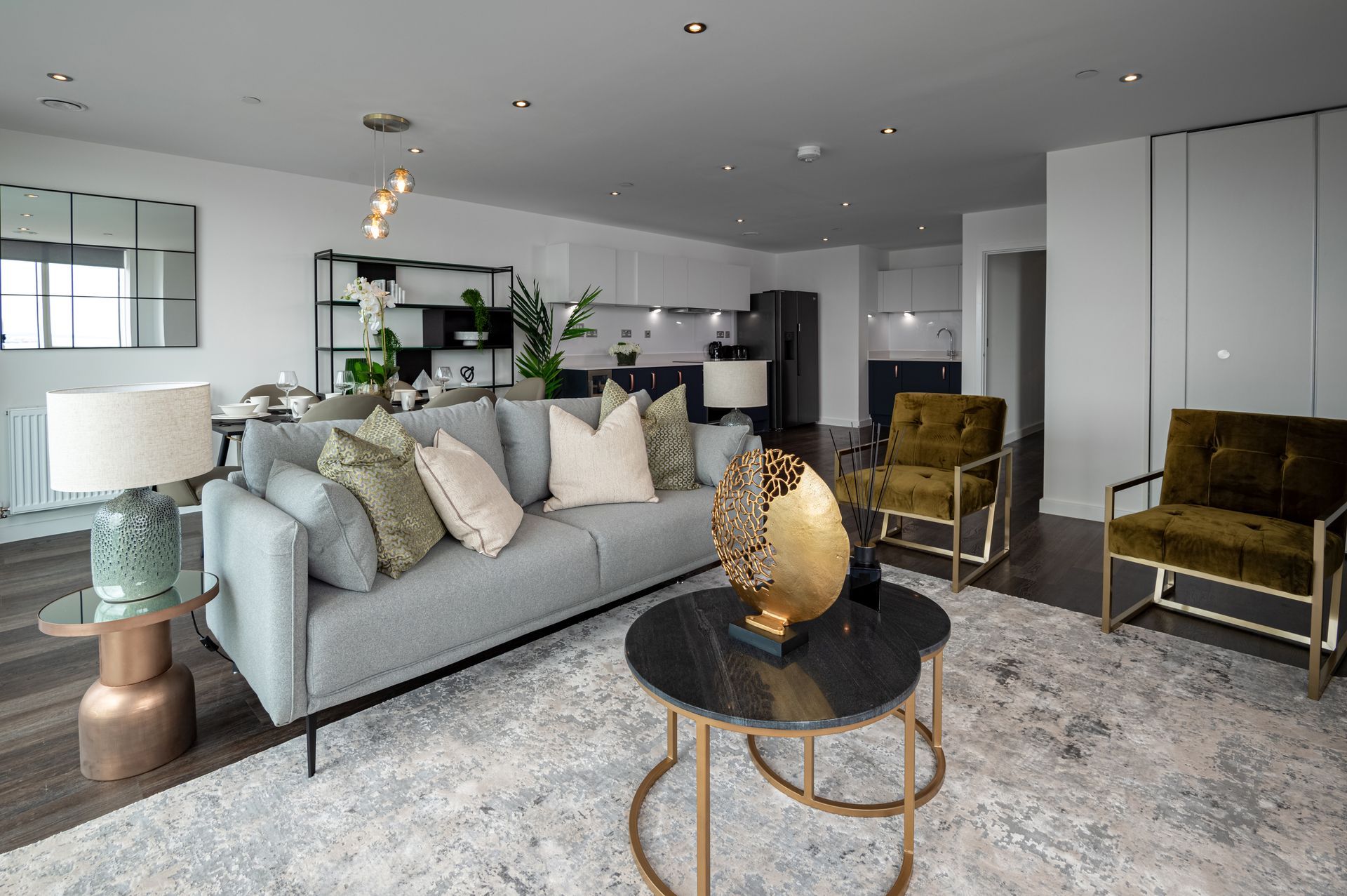 Modern open-concept living room with gray sofa, patterned chairs, round coffee table, and light decor