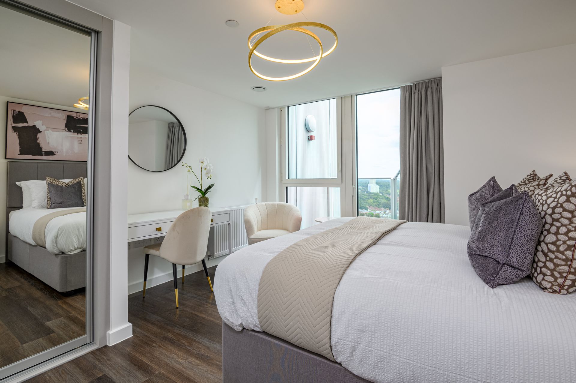 Modern bedroom with a bed, desk, mirror, and large window with gray curtains