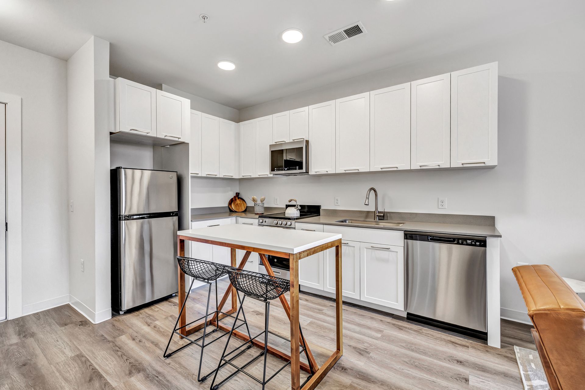 Modern white kitchen with stainless steel appliances and a small central island