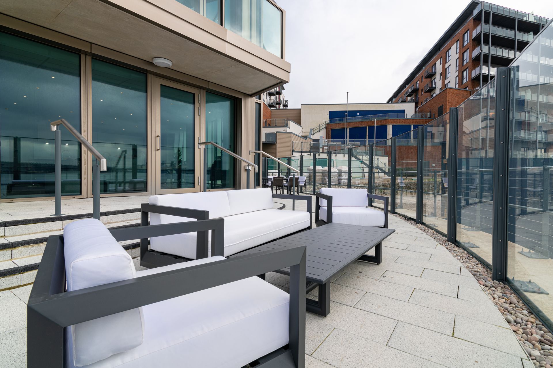 A patio with a couch and chairs in front of a building