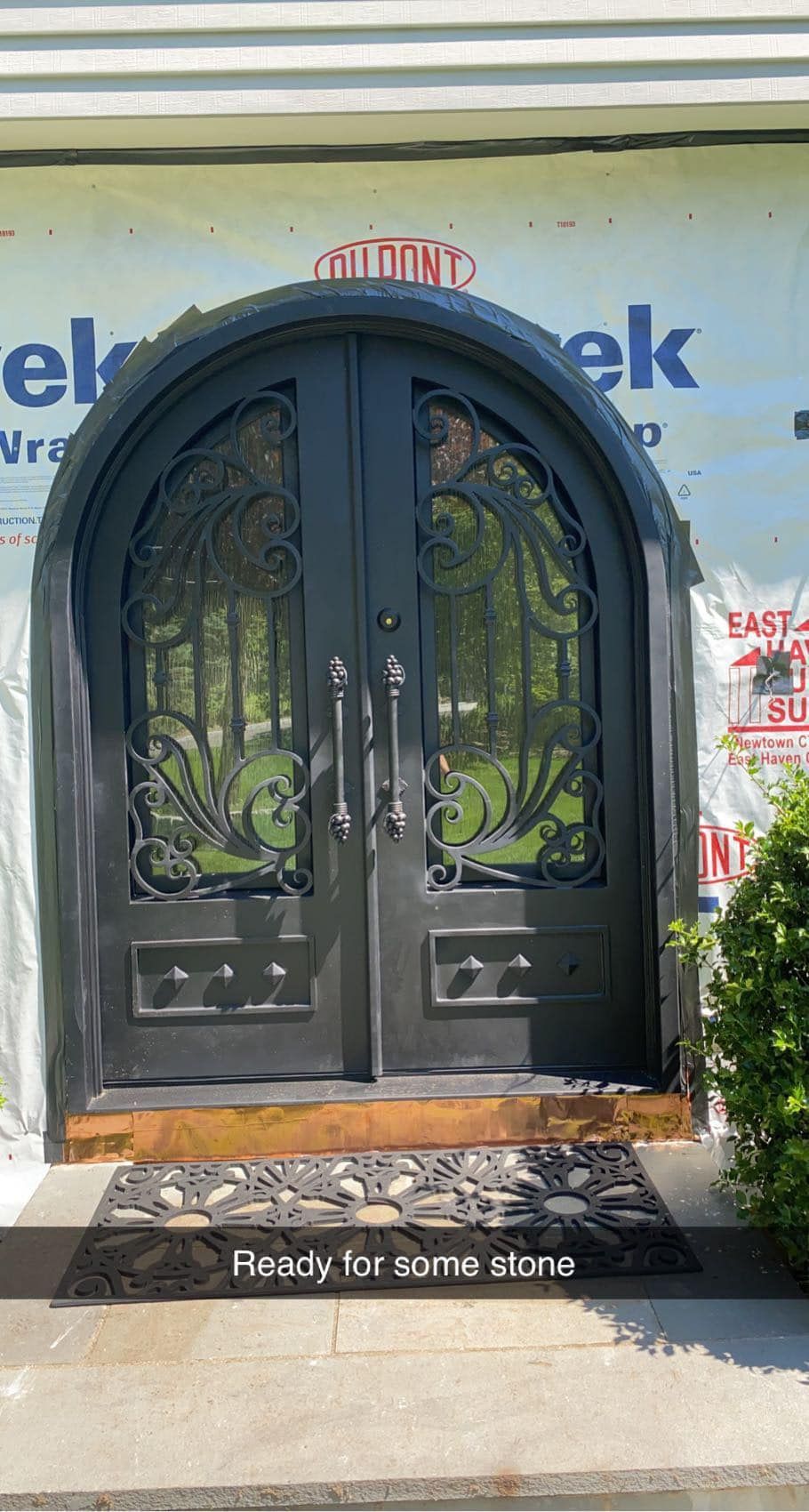 Black arched double storefront doors with decorative glass on a sidewalk