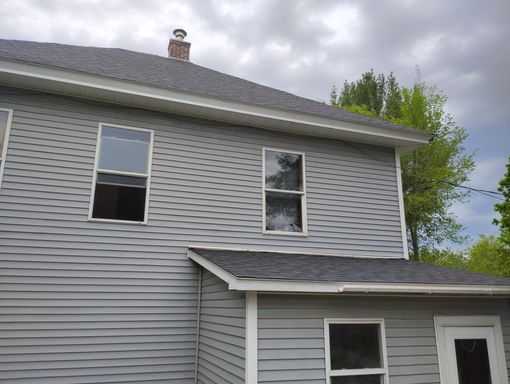 Gray two-story house with vinyl siding, white trim, and a small roof over the lower entry.