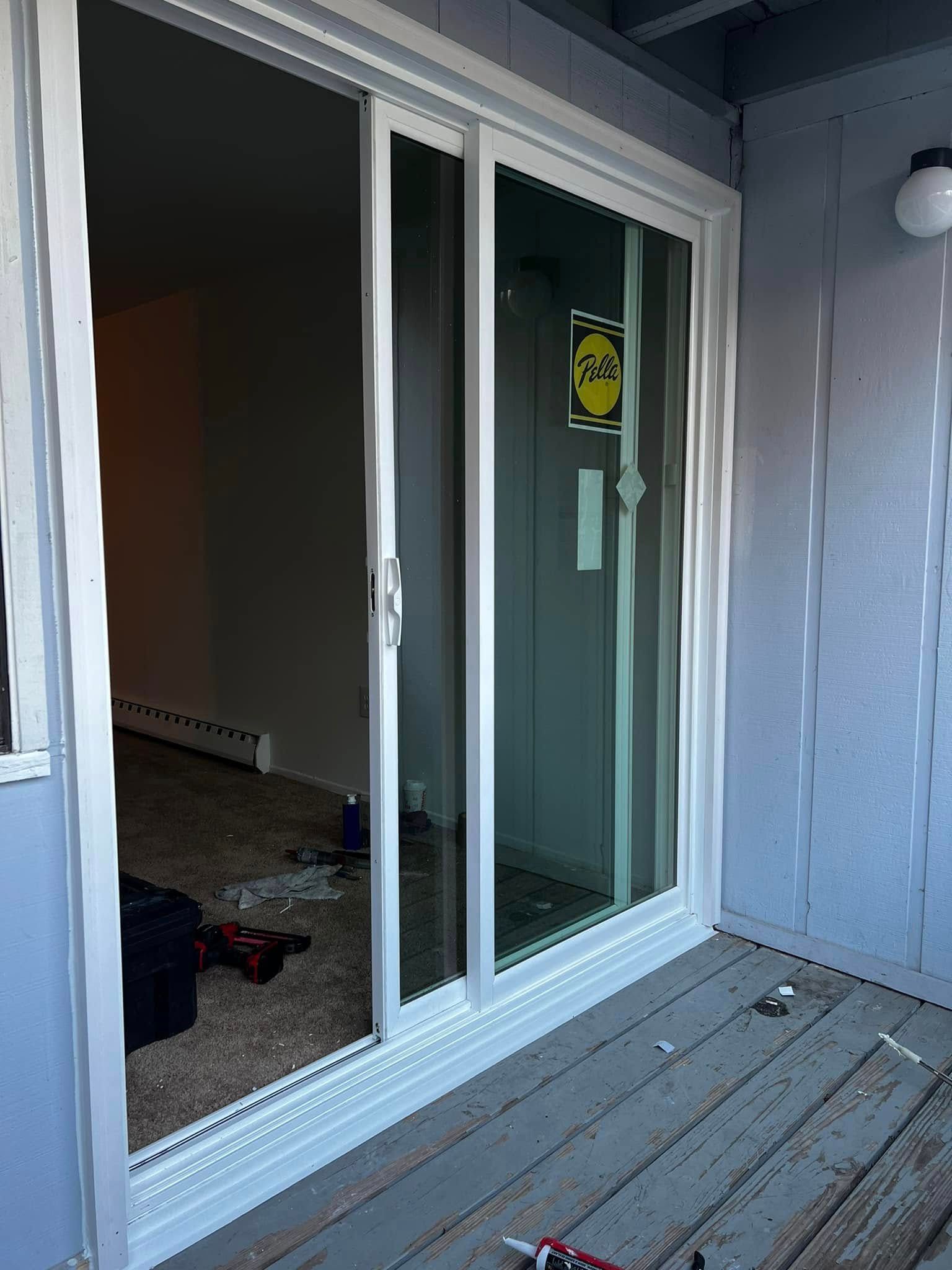 Sliding glass door opening onto a cluttered porch and partially furnished room inside.
