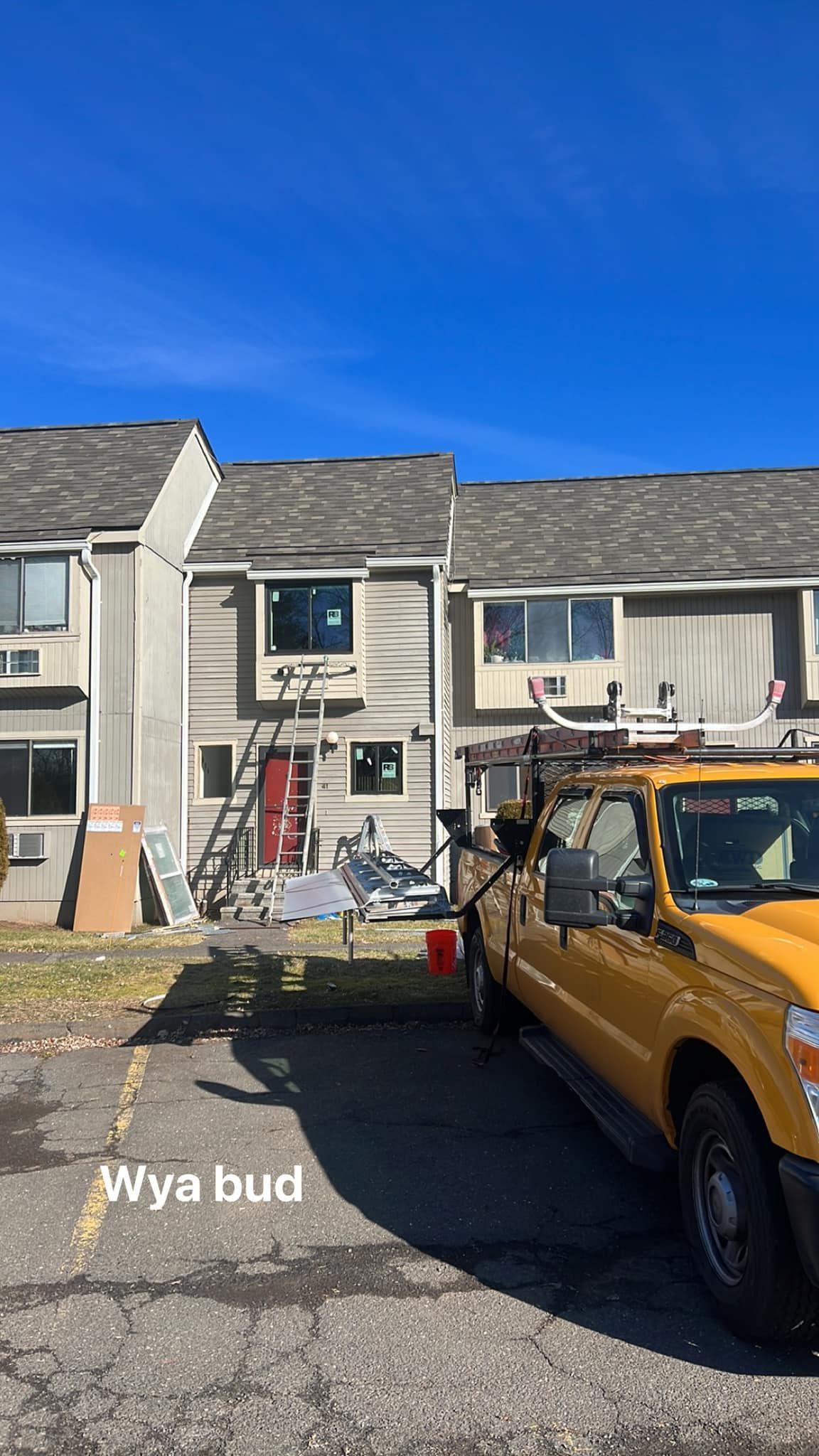 Residential row houses with a yellow Jeep parked in front under a bright blue sky