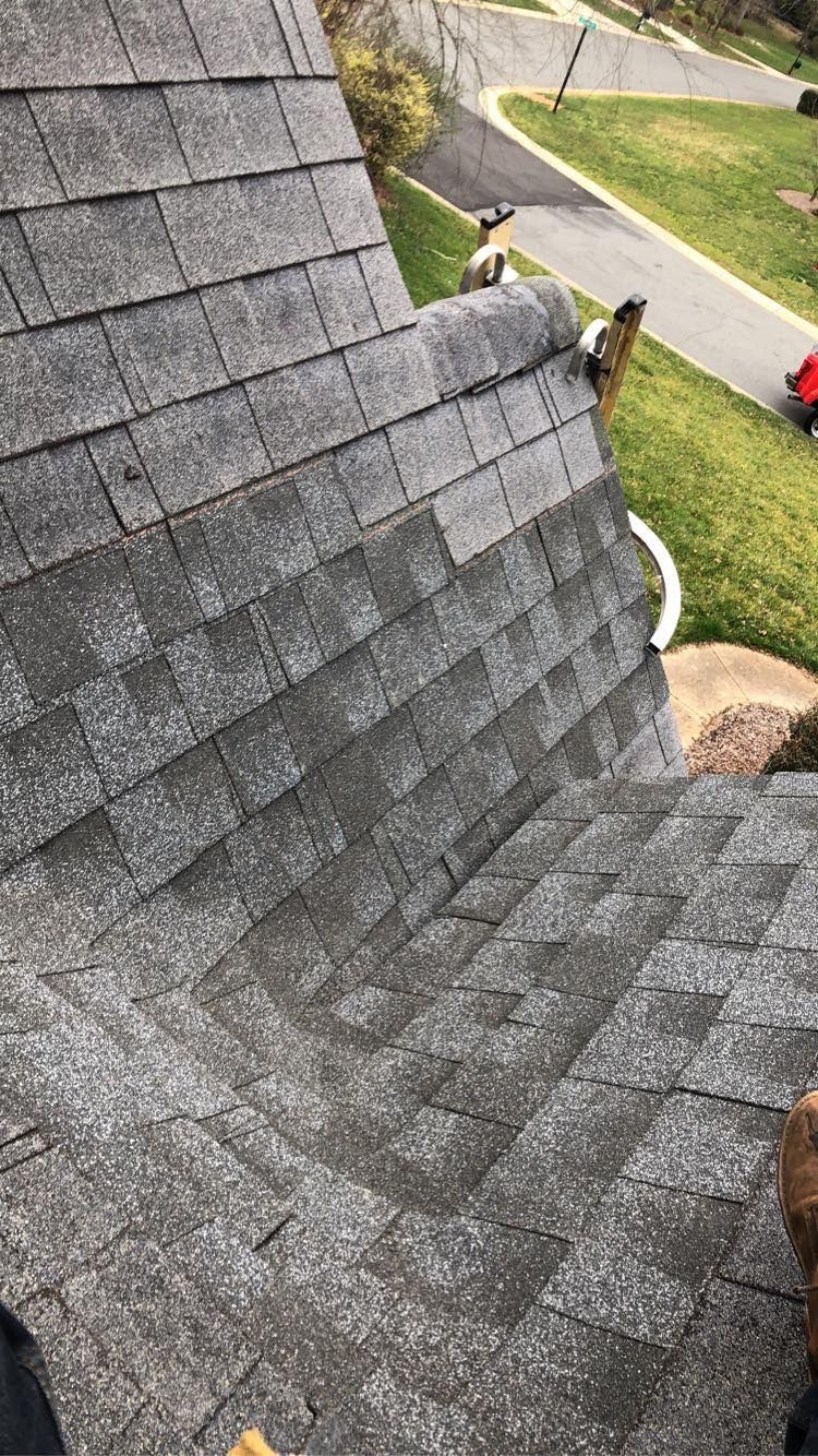 Close-up of gray shingle roof on a house, viewed from above, with lawn and driveway below