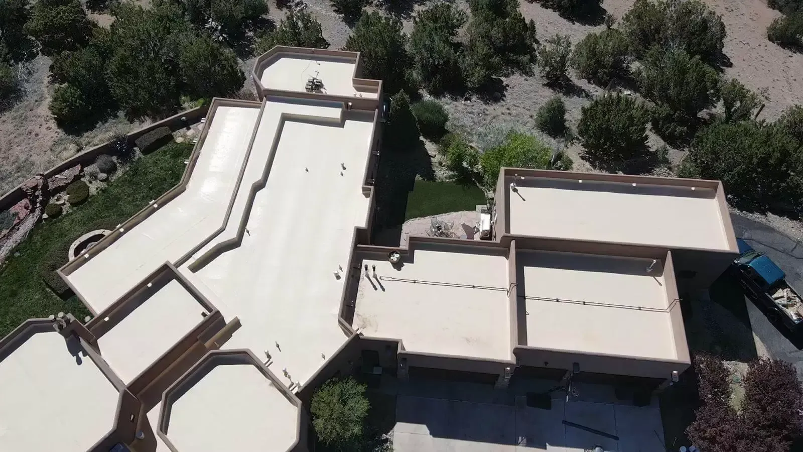 Aerial view of a tan-roofed building complex surrounded by trees and walkways