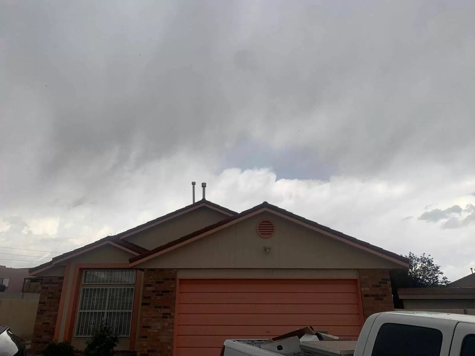 Suburban house with orange garage door under cloudy gray sky