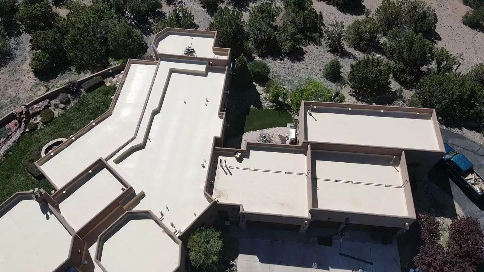 Aerial view of a beige residential complex with flat roofs and surrounding trees