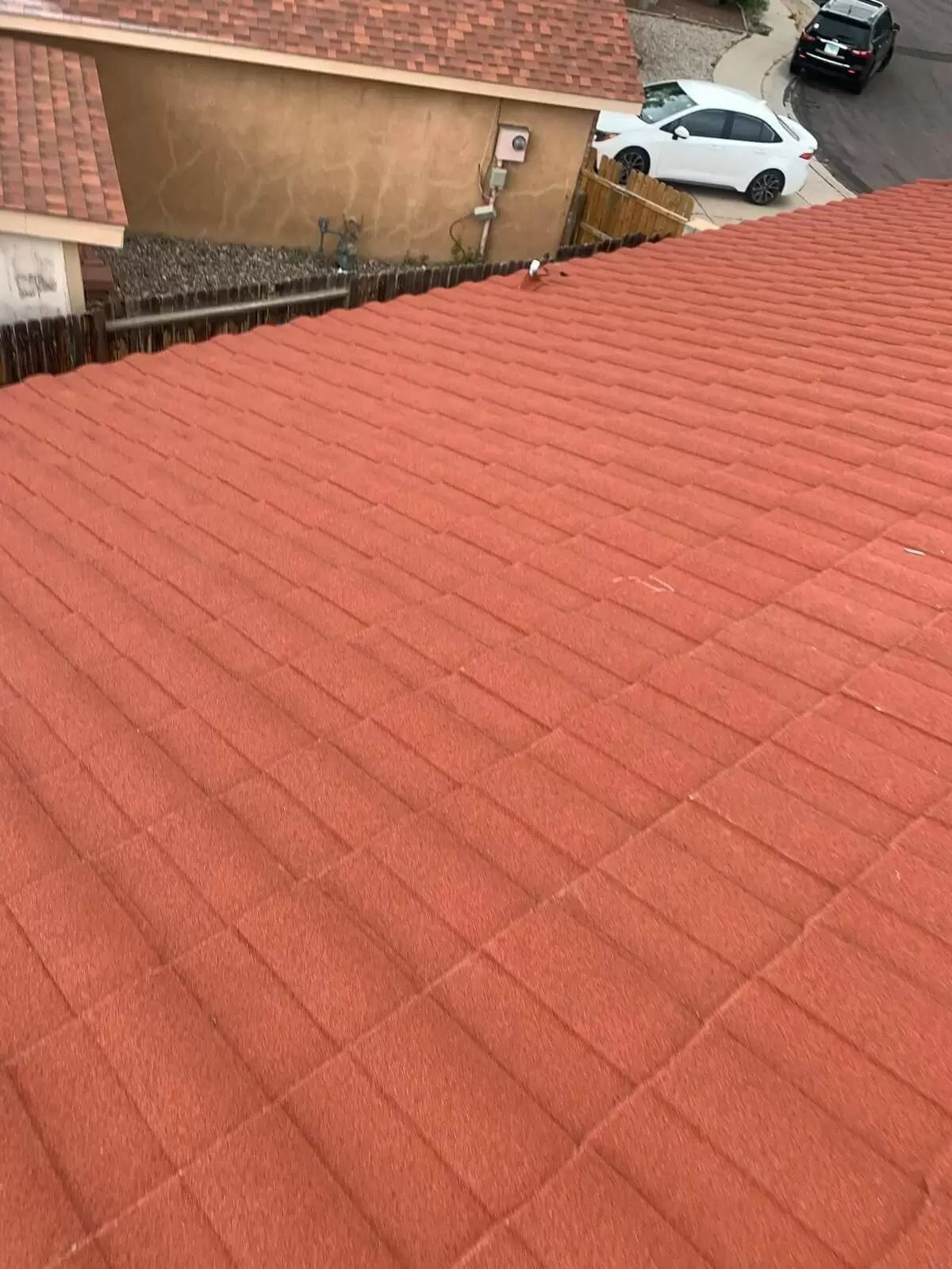 Red-tiled rooftop overlooking a small parking area and beige buildings.