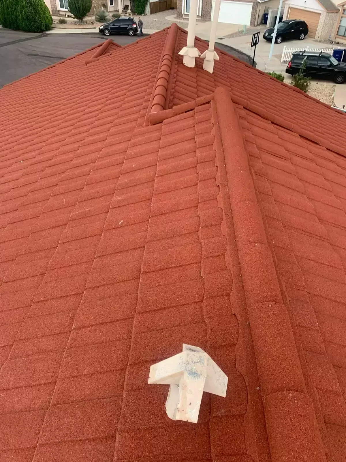 Red tiled roof with white vents and a taped patch in the foreground
