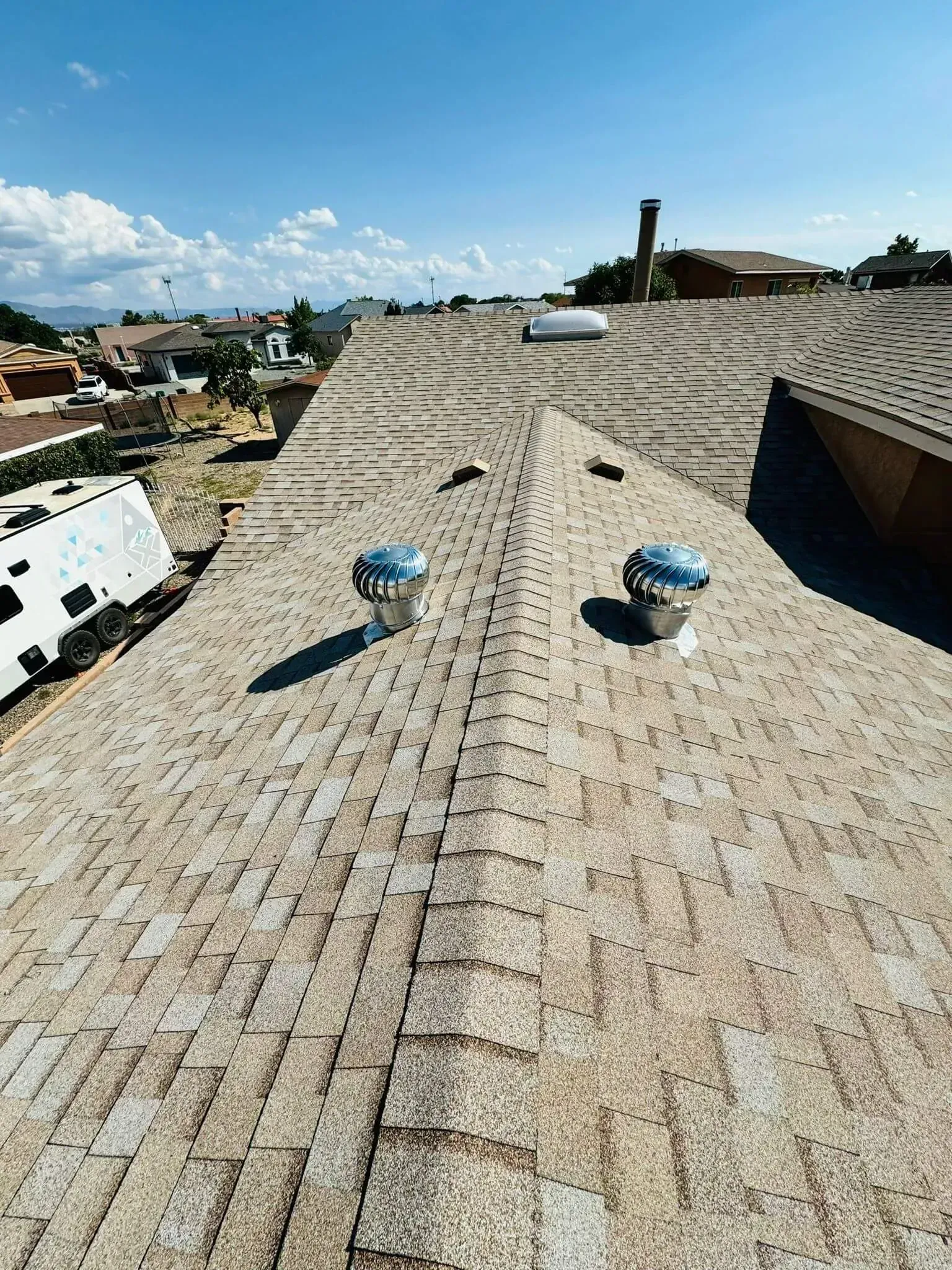 Rooftop with tiled surface, blue vents, and city skyline under a bright blue sky
