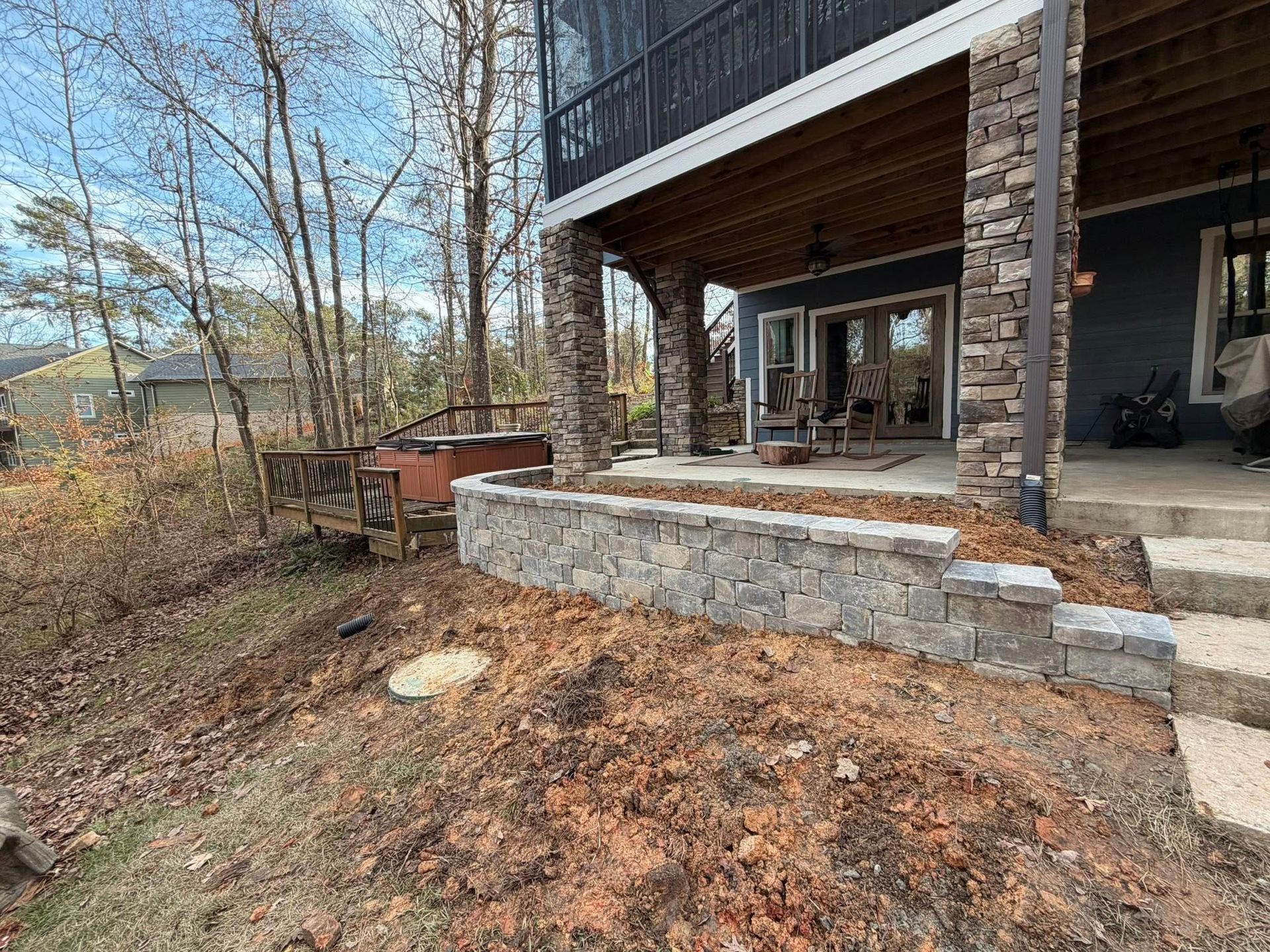Rustic house porch with stone retaining wall overlooking a wooded yard