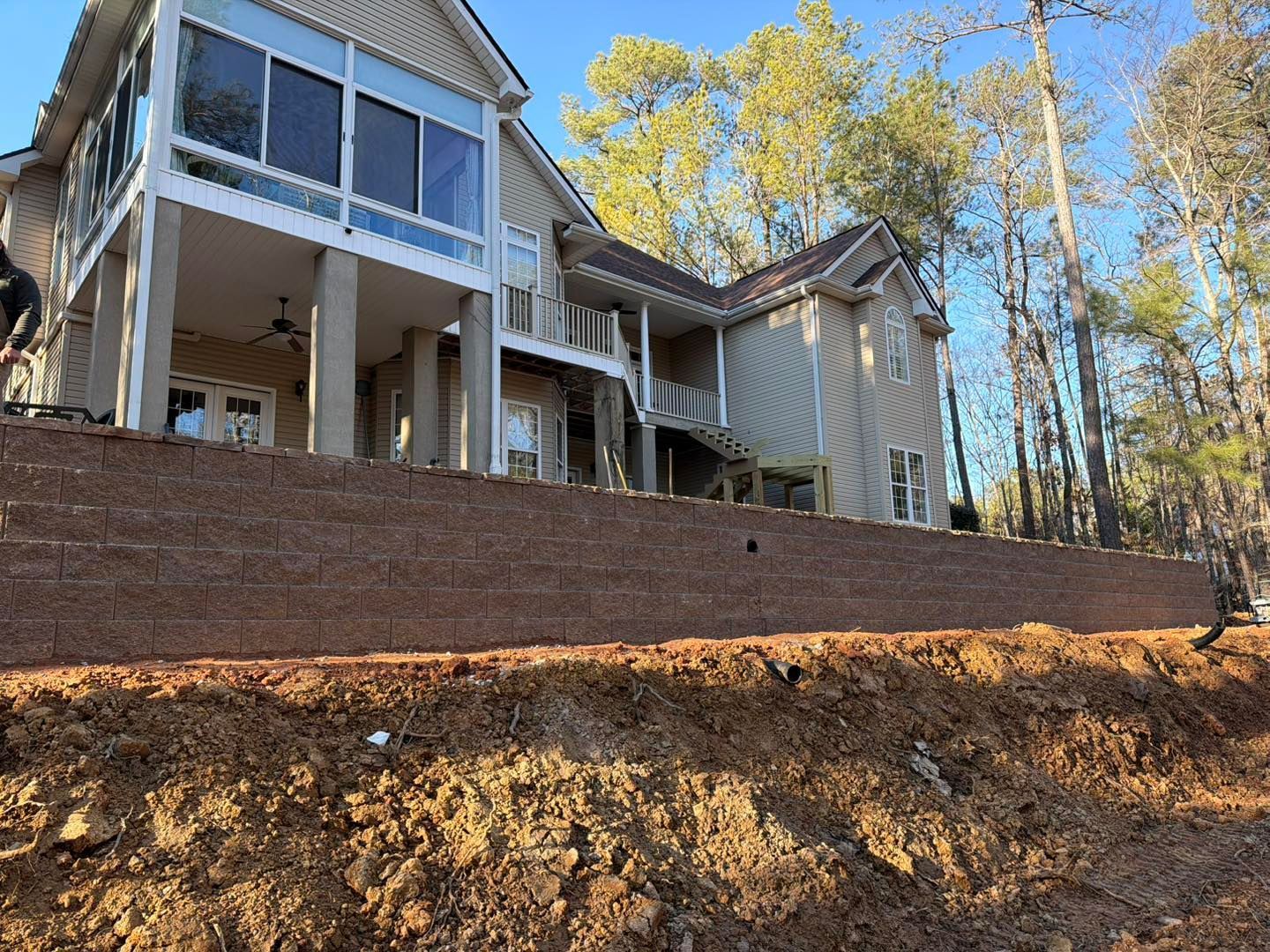 House with screened porch on a steep wooded hillside, viewed from below.