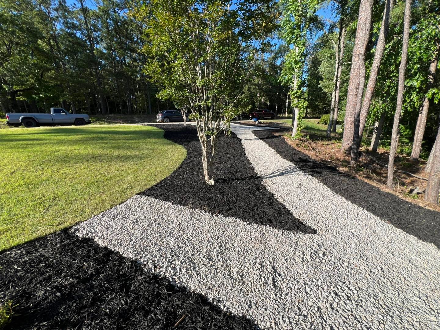 Curved gravel path beside a grassy lawn and trees in a sunny yard