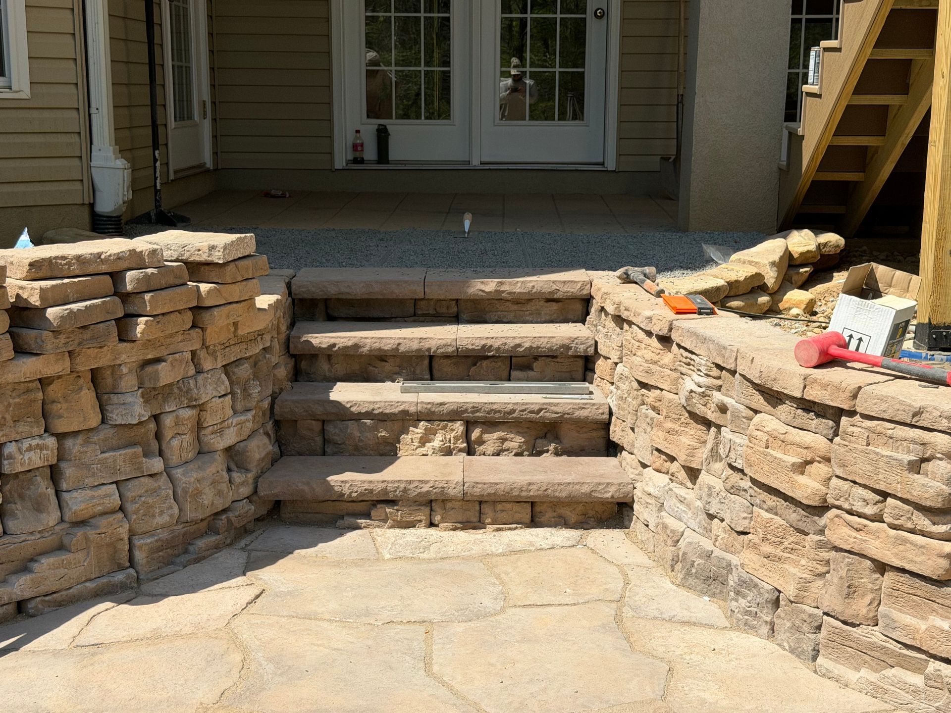 Stone steps leading to a porch, with stacked stone retaining walls on both sides.
