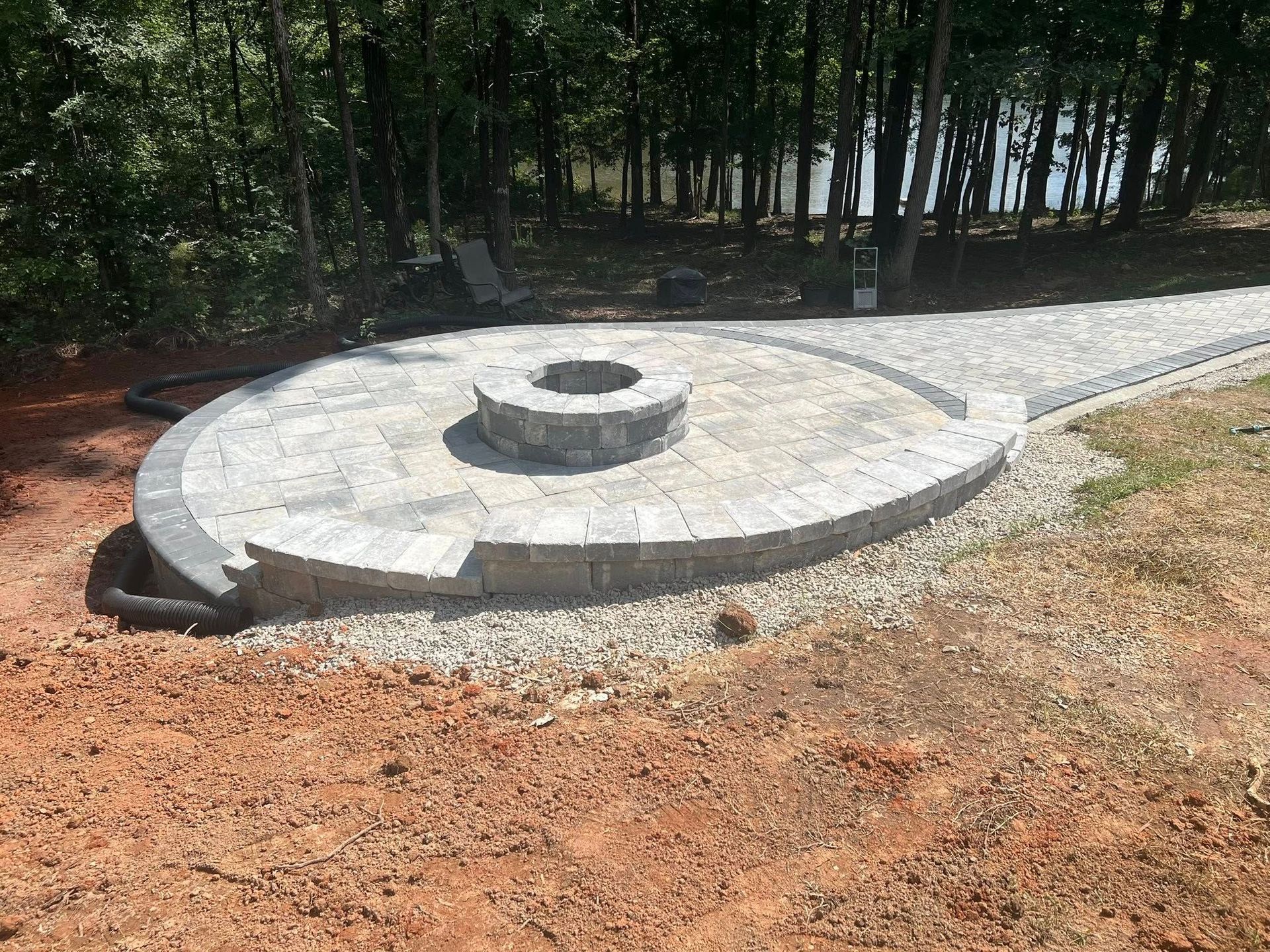 Circular concrete structure with a central raised ring beside a gravel path in a wooded area