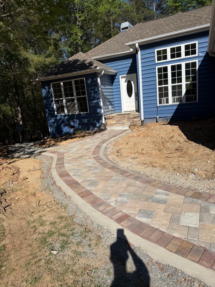 Curved brick and stone walkway leading to a blue house with white trim and a front door