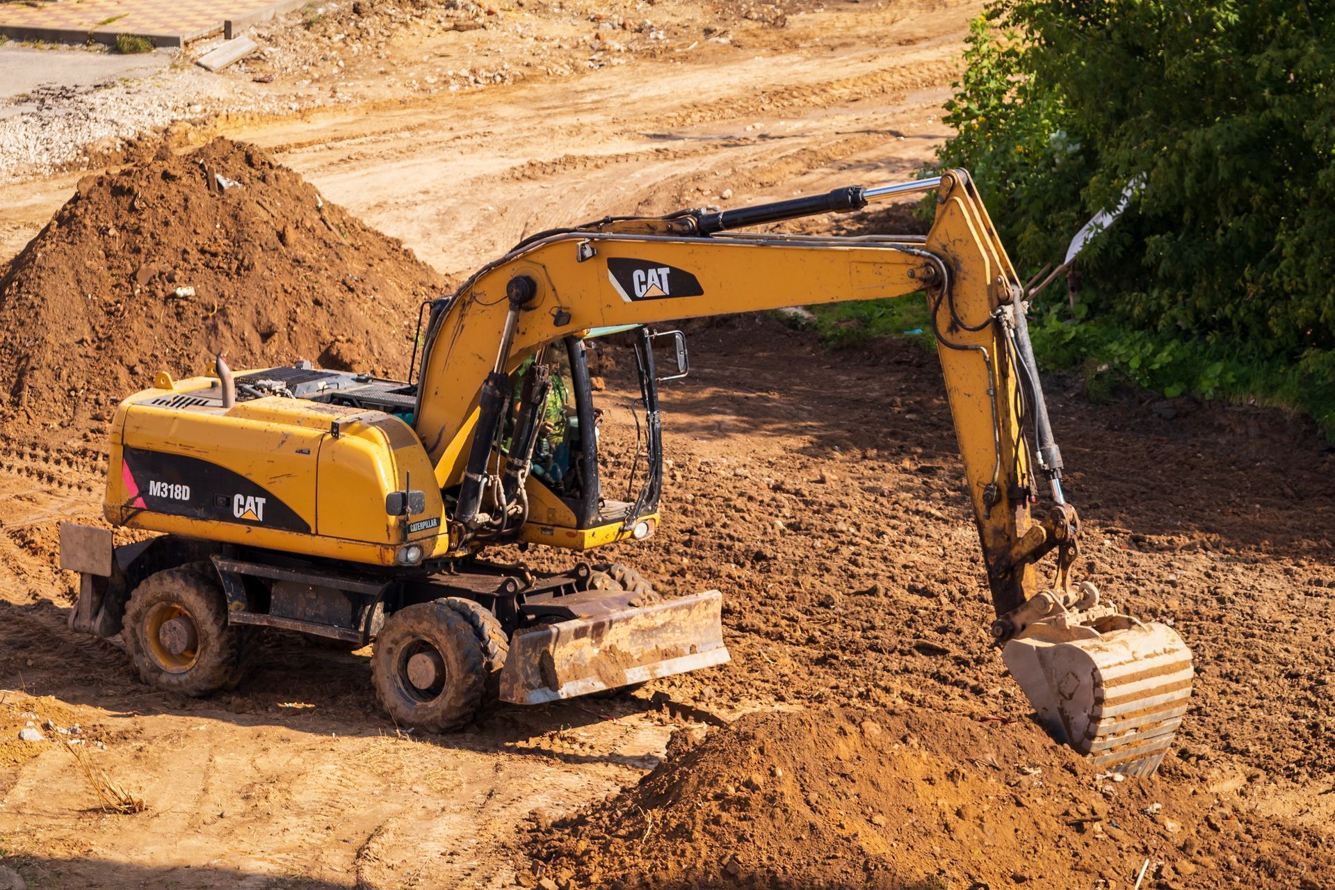 Yellow excavator digging dirt on a construction site beside a muddy embankment