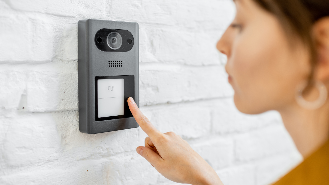 A woman is pressing a button on an intercom system.