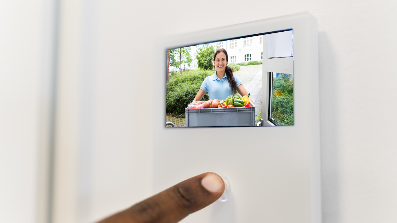 A person is holding a video intercom system in front of a door.