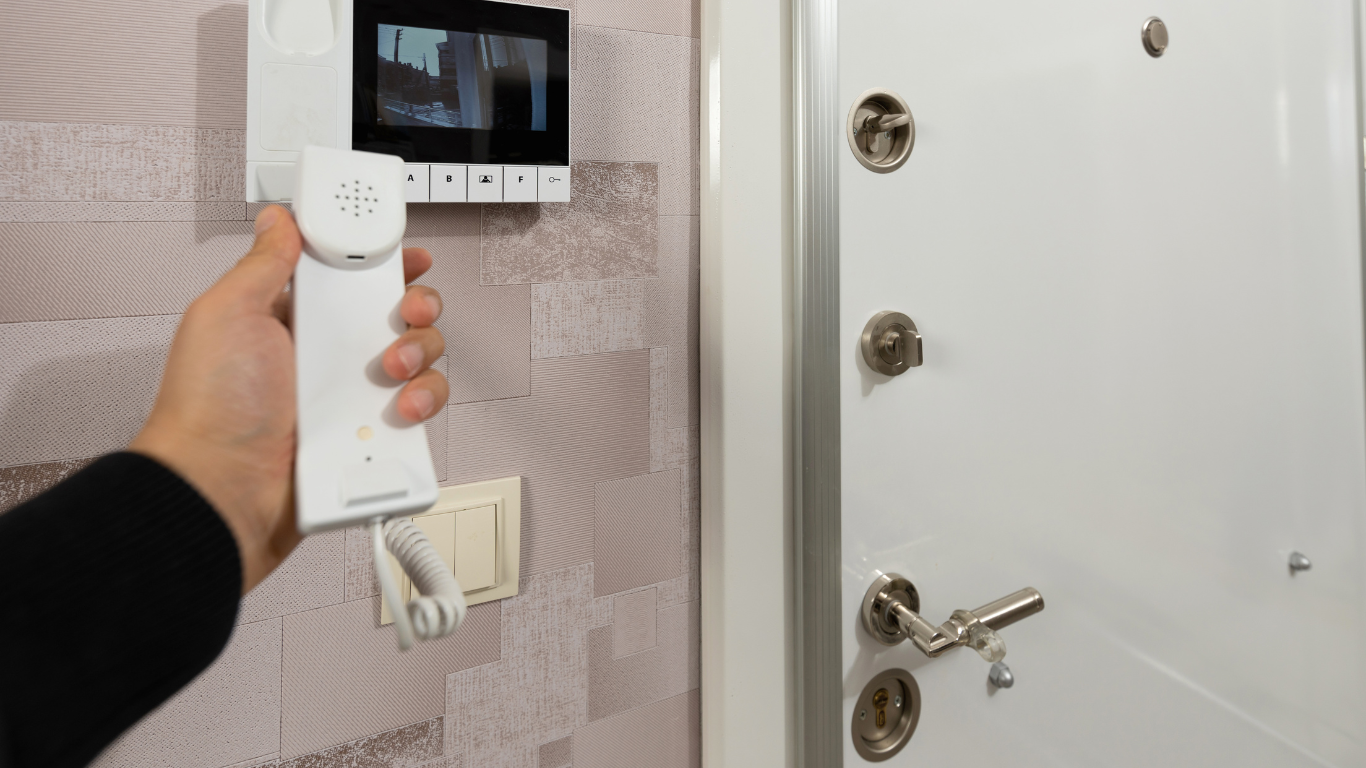 A person is holding an intercom in front of a door.