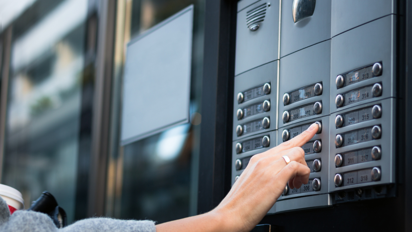 A person is pressing a button on an intercom system.
