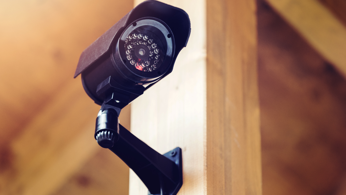 A video surveillance camera is mounted on a wooden pole.