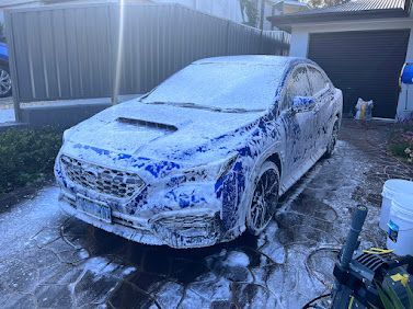 White Sedan Covered In SOAP Foam In A Driveway, Being Washed Outdoors — Car Detailing Mobile Cleaning Co In Port Macquarie, NSW