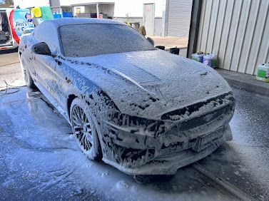 Grey Sedan Covered In Thick Foam During A Car Wash, Parked Outdoors On Wet Pavement — Car Detailing Mobile Cleaning Co In Port Macquarie, NSW