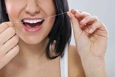 Woman Using Dental Floss — Orange, CT — New England Dental Health Services PC Woman Using Dental Floss — Orange, CT — New England Dental Health Services PC