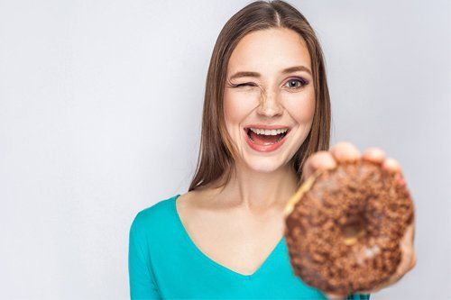 Woman Holding a Donut — Orange, CT — New England Dental Health Services PC Woman Holding a Donut — Orange, CT — New England Dental Health Services PC