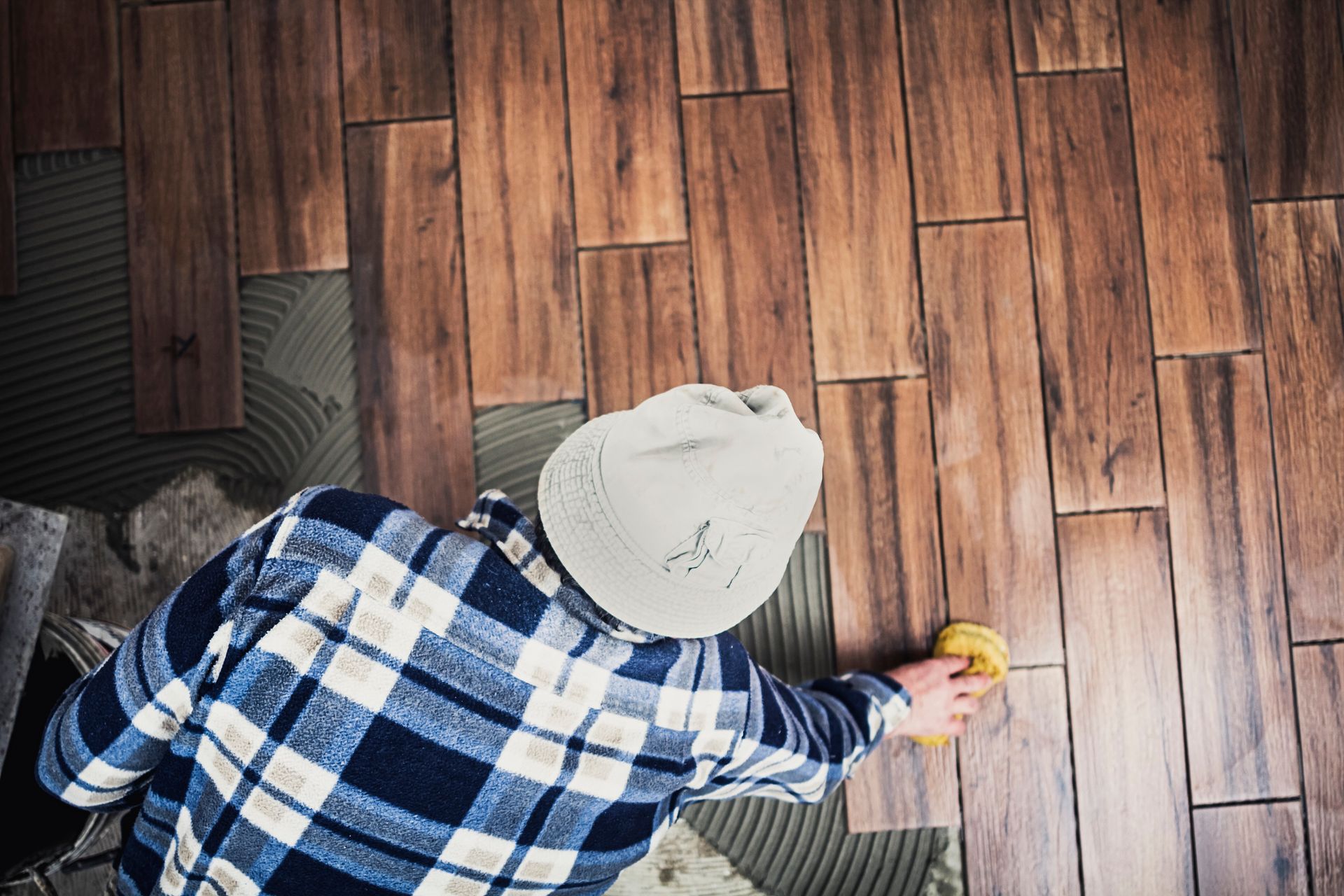 A man is cleaning a wooden floor with a sponge.