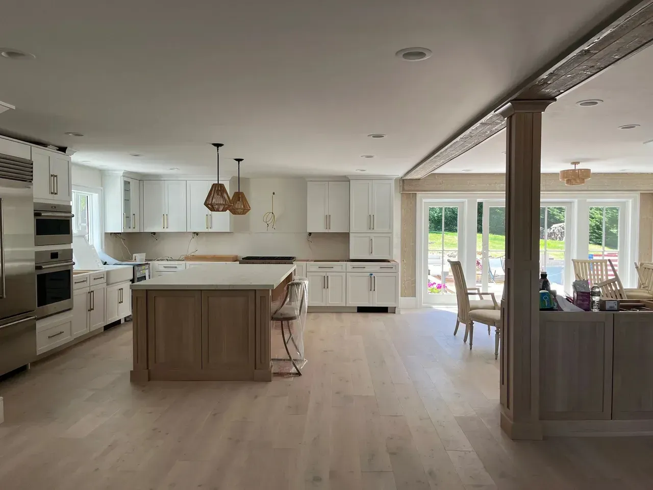 A kitchen with white cabinets and stainless steel appliances and a large island in the middle of the room.