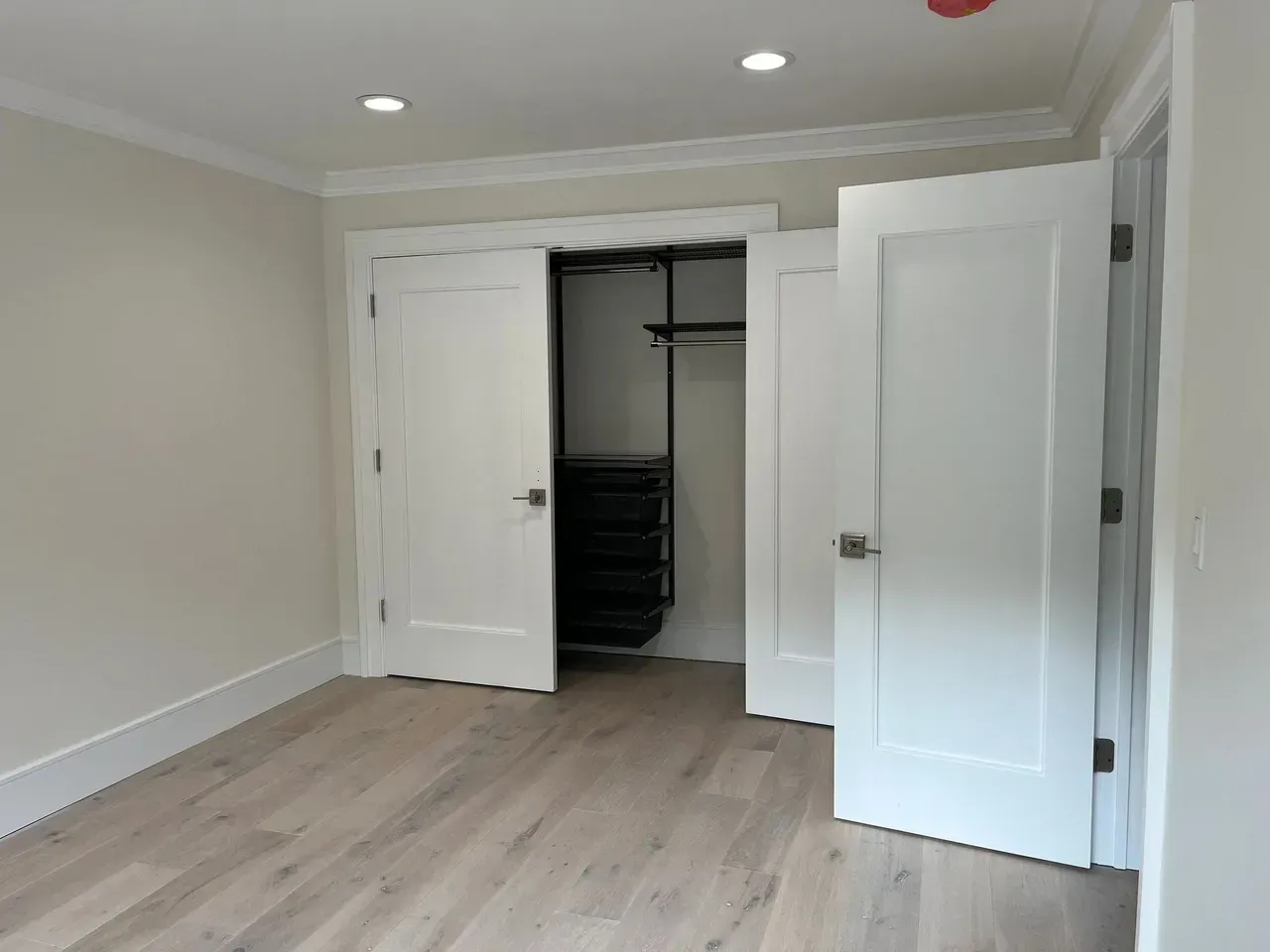 An empty room with white doors and a closet