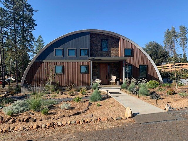 A house with a curved roof is surrounded by trees