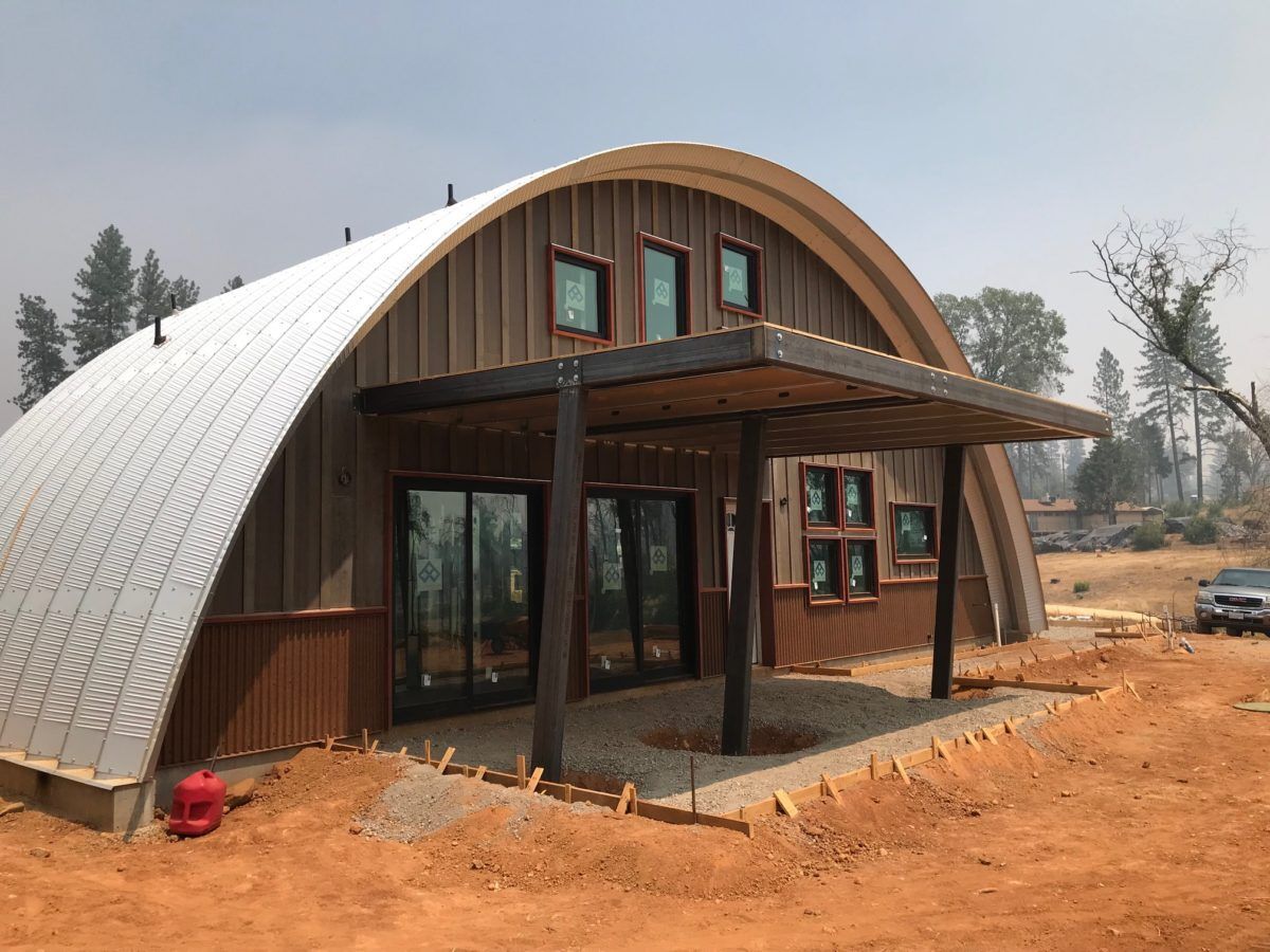 A large house is being built in the middle of a dirt field.