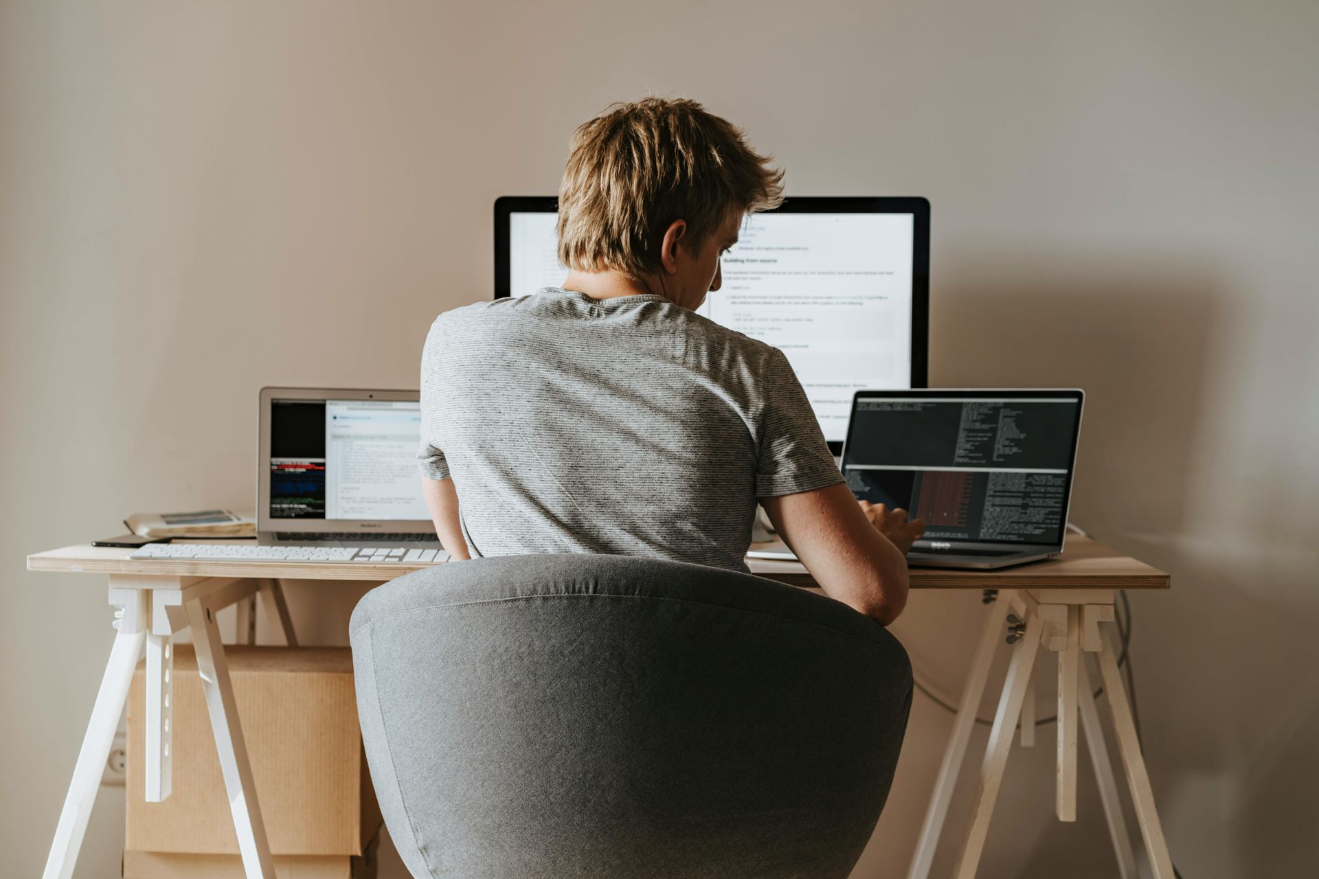 Person working on multiple computers at a desk.