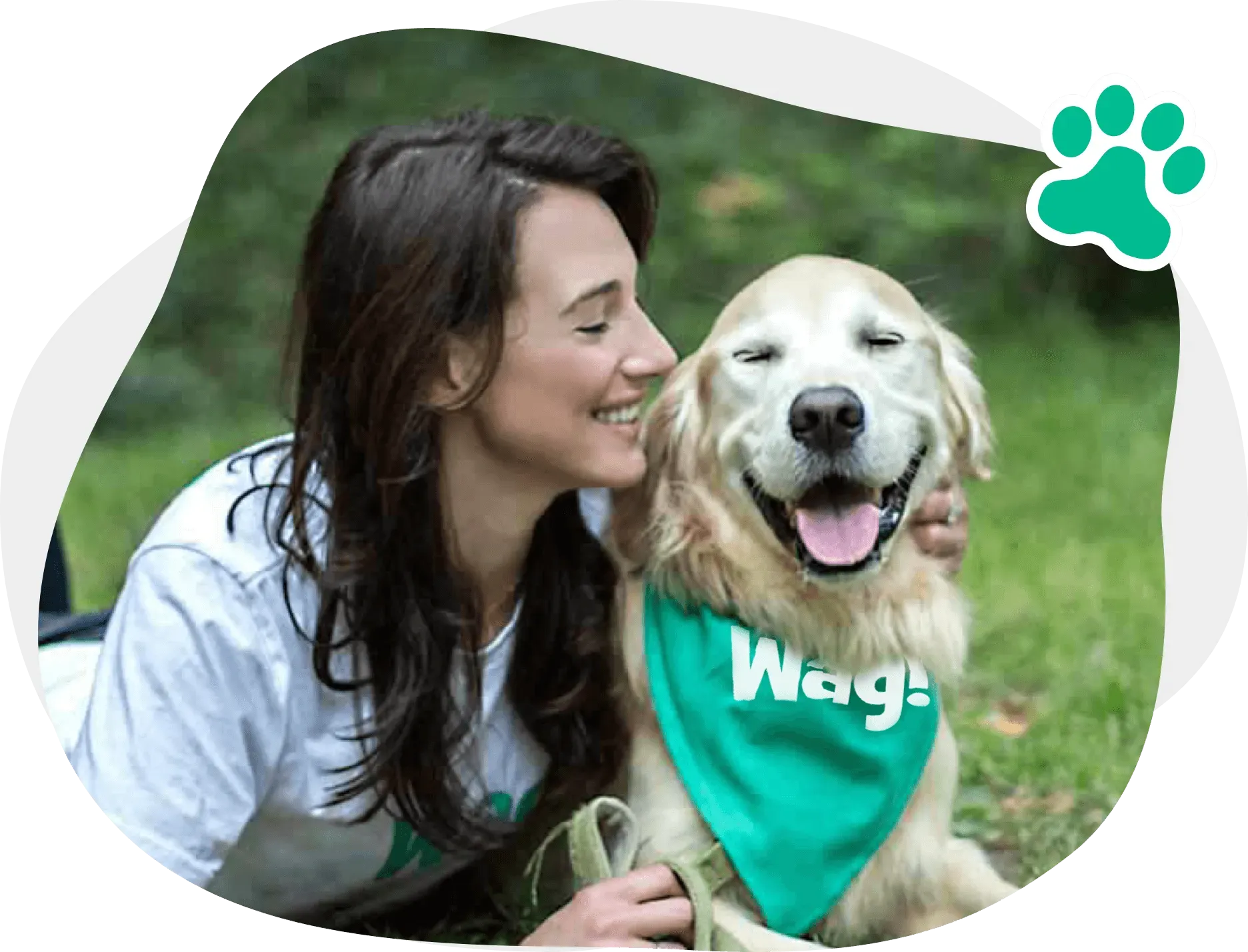 Woman smiles while petting a golden retriever wearing a green