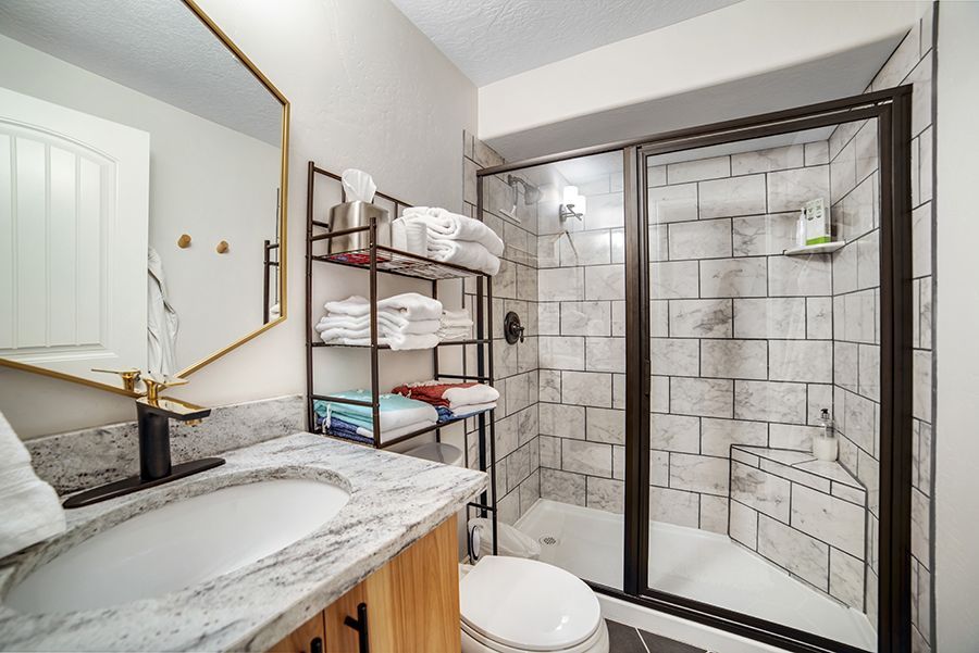 a bathroom with a sink , toilet , shower and mirror .