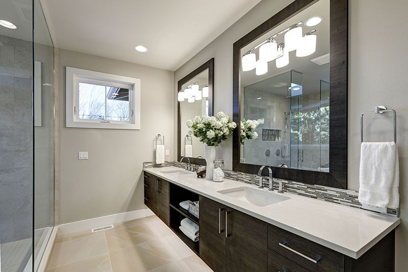 a bathroom with two sinks, two mirrors and a walk in shower.