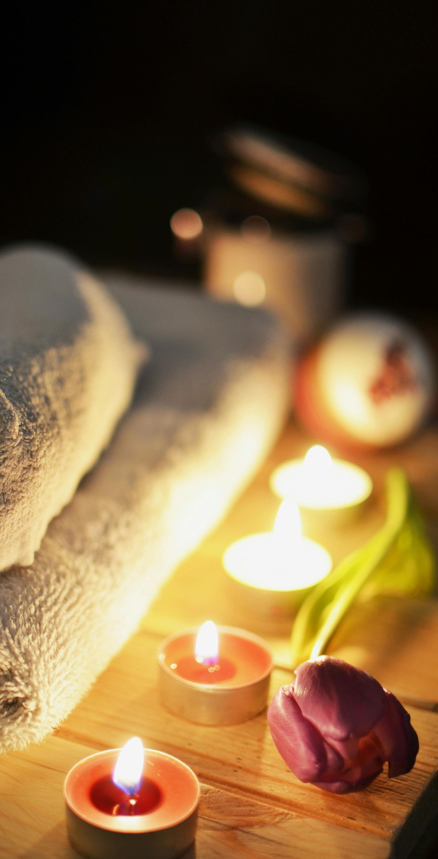 Towels, candles, and a tulip arranged on wood, creating a spa-like ambiance.