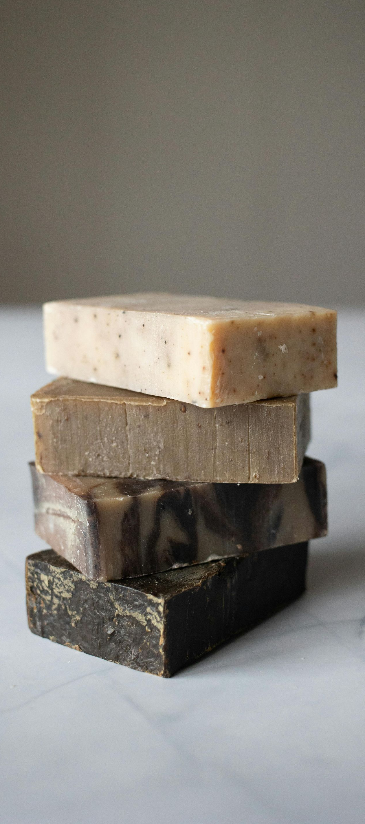 Four rectangular bars of soap stacked on top of each other against a light gray background.