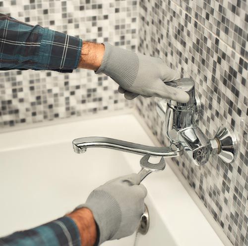 Man Fixing The Faucet In Bathroom Man Fixing The Faucet In Bathroom