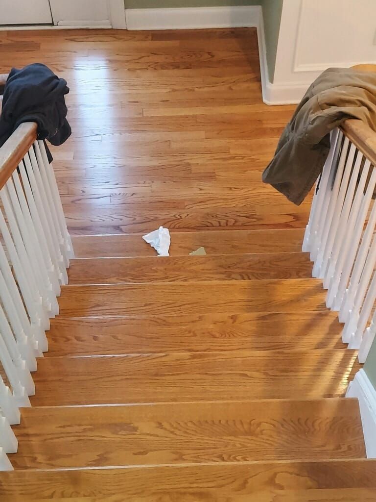 A wooden staircase with a white railing and a piece of paper on the floor