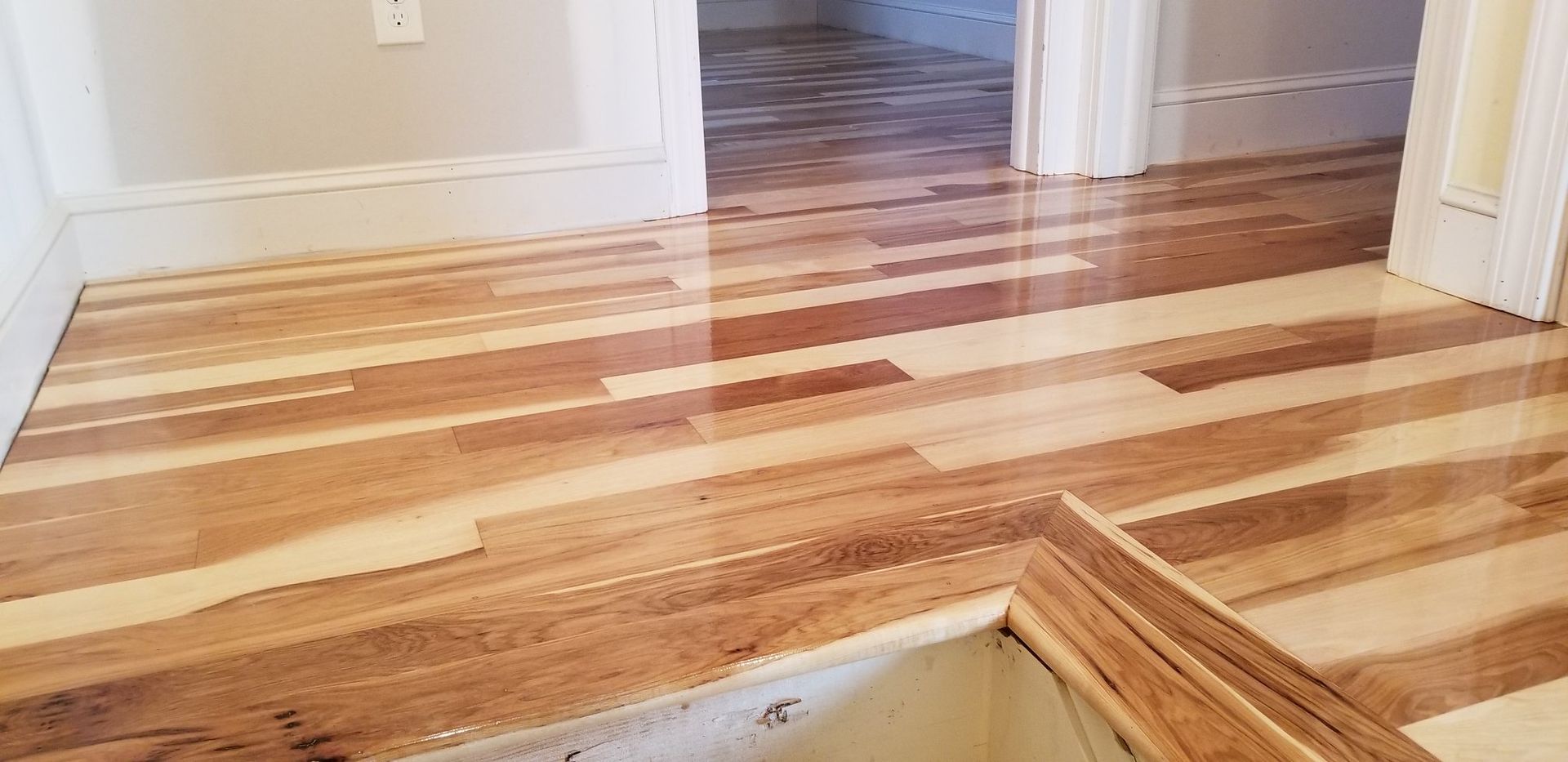 A wooden floor in a room with a door in the background.