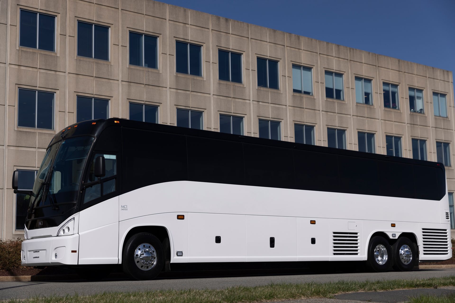 A white and black bus is parked in front of a building