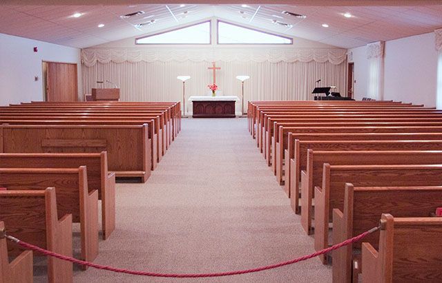 the inside of an empty church with wooden benches and a piano .