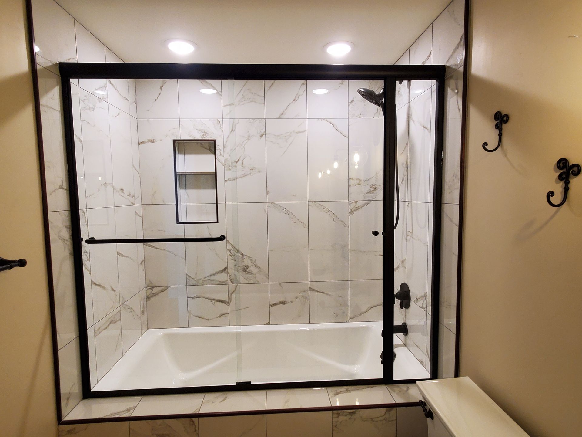 Modern bathroom with a glass-enclosed tub shower and marble-pattern tile surround