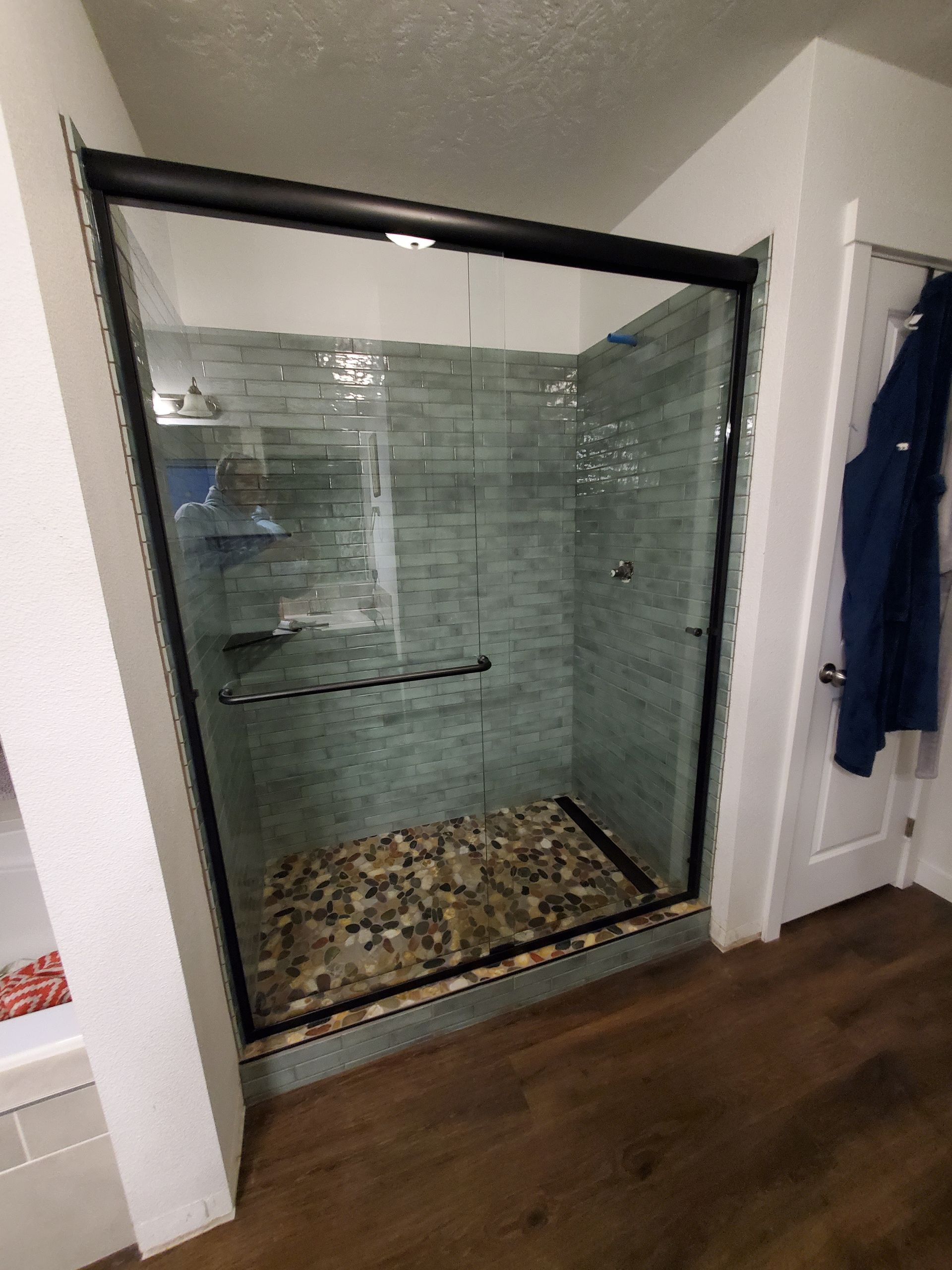 Walk-in glass shower with pebble floor and tiled walls in a bathroom
